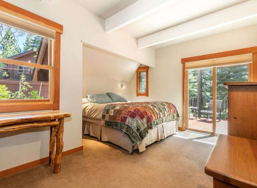 Experience cozy mountain living in this charming bedroom, featuring a comfortable bed adorned with a rustic patchwork quilt.