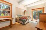 Experience cozy mountain living in this charming bedroom, featuring a comfortable bed adorned with a rustic patchwork quilt.