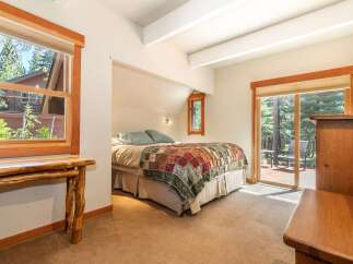 Experience cozy mountain living in this charming bedroom, featuring a comfortable bed adorned with a rustic patchwork quilt.