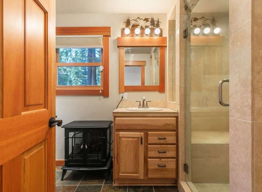 This charming bathroom features a rustic wooden vanity with ample storage, complemented by a large mirror and a decorative light fixture.