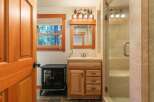 This charming bathroom features a rustic wooden vanity with ample storage, complemented by a large mirror and a decorative light fixture.
