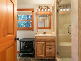 This charming bathroom features a rustic wooden vanity with ample storage, complemented by a large mirror and a decorative light fixture.