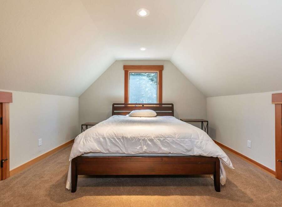 Discover this charming bedroom featuring a cozy queen-size bed with a plush white duvet, perfect for restful nights.