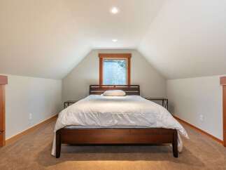 Discover this charming bedroom featuring a cozy queen-size bed with a plush white duvet, perfect for restful nights.