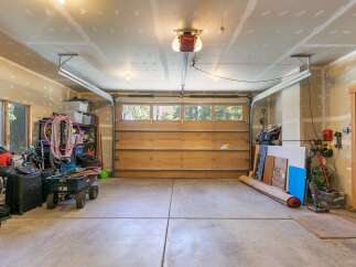 This spacious garage offers ample storage solutions with shelving units and plenty of floor space for vehicles and equipment.