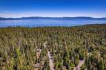 Discover your dream mountain retreat nestled amidst a dense forest with stunning views of a vast, blue lake and distant mountains.