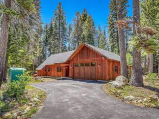 Nestled amongst tall pine trees, this charming wooden home offers a serene retreat.