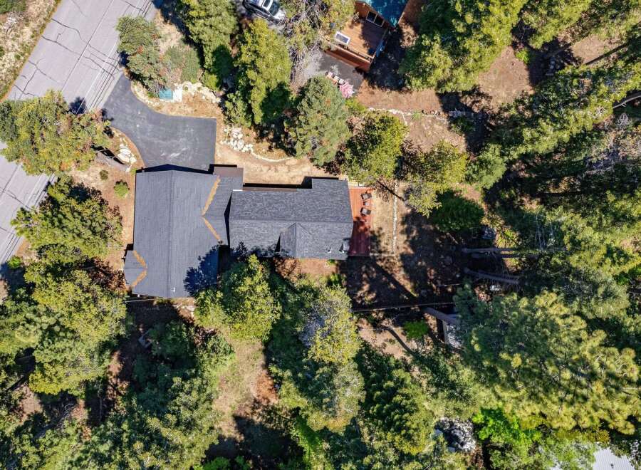 Discover this stunning aerial view of a modern home nestled amongst lush green trees.