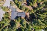 Discover this stunning aerial view of a modern home nestled amongst lush green trees.