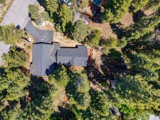 Discover this stunning aerial view of a modern home nestled amongst lush green trees.