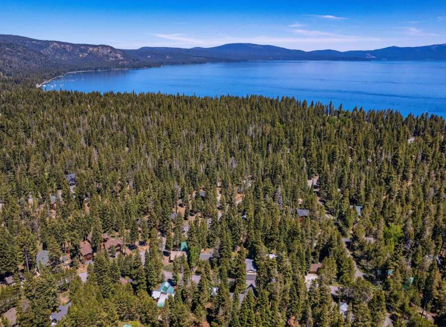 Nestled amidst a dense forest of mature pine trees, this property offers a secluded retreat with stunning views of a vast, blue lake and distant mountains.