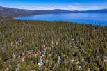 Nestled amidst a dense forest of mature pine trees, this property offers a secluded retreat with stunning views of a vast, blue lake and distant mountains.