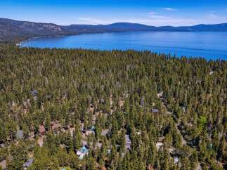Nestled amidst a dense forest of mature pine trees, this property offers a secluded retreat with stunning views of a vast, blue lake and distant mountains.