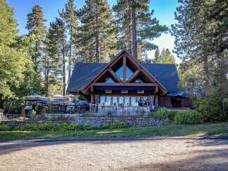 Experience lakeside dining at this stunning property, featuring a rustic A-frame lodge with expansive windows overlooking the water.