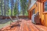Enjoy outdoor living on this spacious wooden deck, perfect for entertaining or relaxing amidst a serene forest setting.