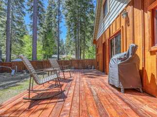 Enjoy outdoor living on this spacious wooden deck, perfect for entertaining or relaxing amidst a serene forest setting.