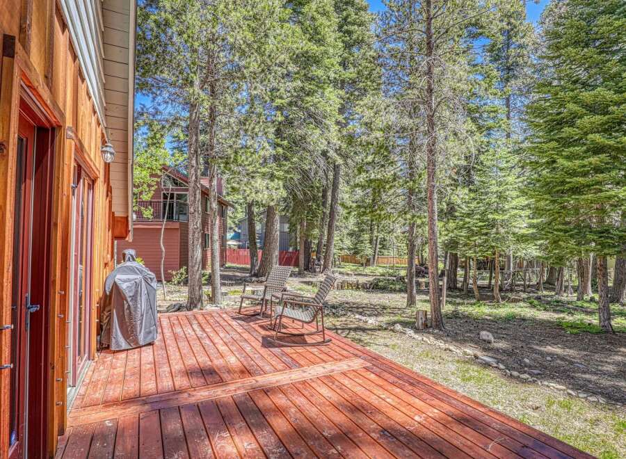 Enjoy outdoor living on this spacious wooden deck, perfect for entertaining or relaxing amidst a serene forest setting.