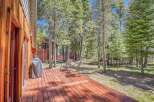 Enjoy outdoor living on this spacious wooden deck, perfect for entertaining or relaxing amidst a serene forest setting.