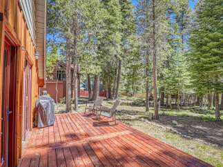 Enjoy outdoor living on this spacious wooden deck, perfect for entertaining or relaxing amidst a serene forest setting.
