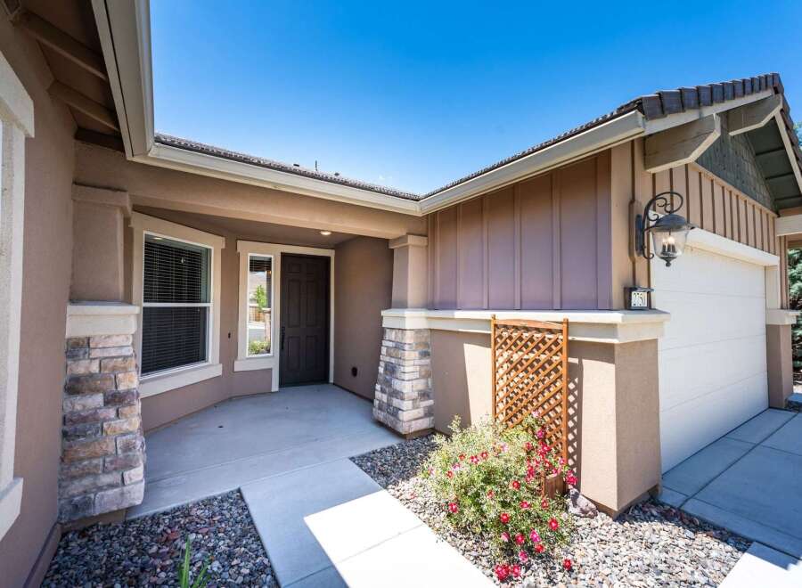 Welcome to this charming home featuring a welcoming covered porch with stone accents and a dark wood front door.