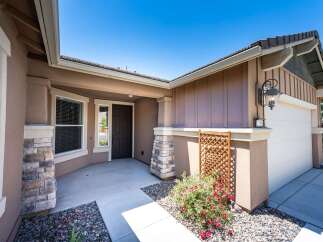 Welcome to this charming home featuring a welcoming covered porch with stone accents and a dark wood front door.