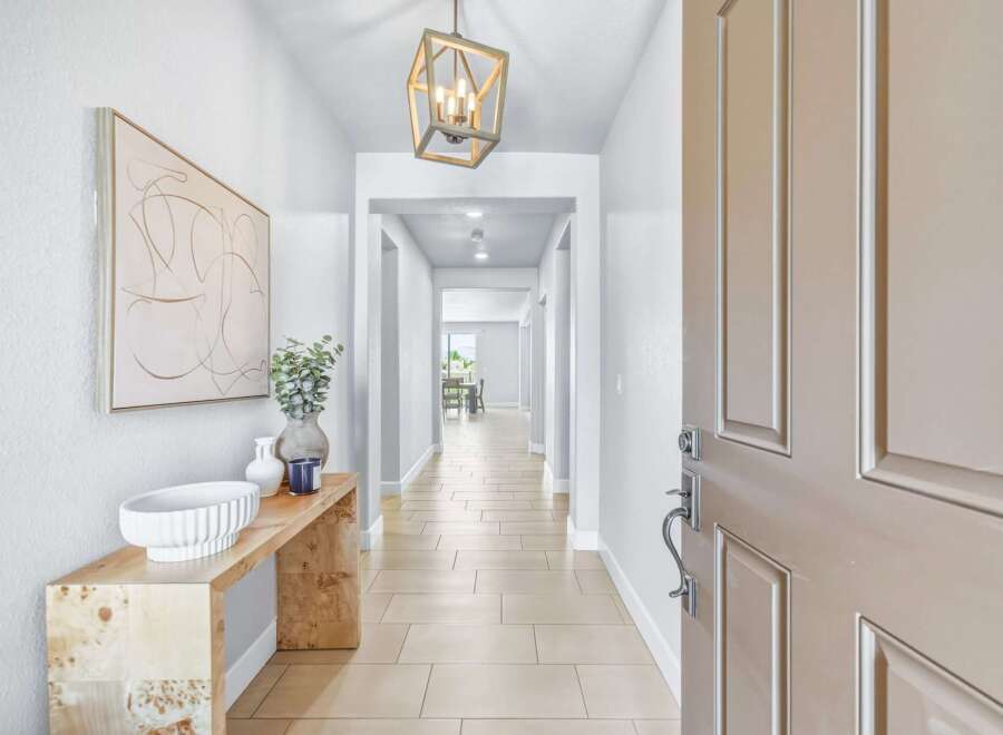Step into this inviting entryway, featuring a stylish console table adorned with decorative vases and a modern abstract artwork.