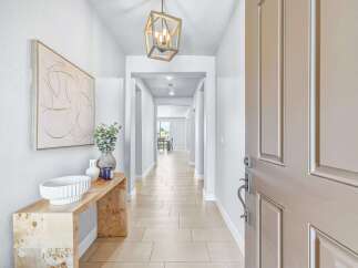 Step into this inviting entryway, featuring a stylish console table adorned with decorative vases and a modern abstract artwork.