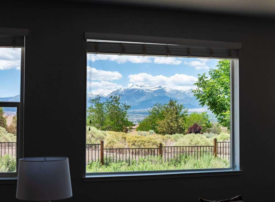 Experience breathtaking mountain views from this stunning property, framed by lush greenery and a clear blue sky.
