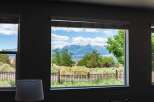 Experience breathtaking mountain views from this stunning property, framed by lush greenery and a clear blue sky.