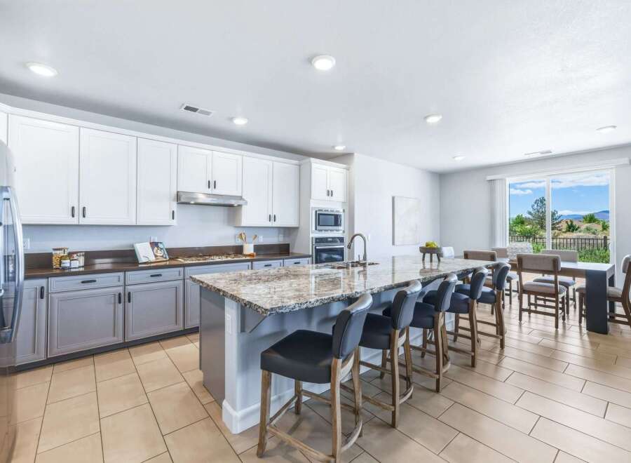 Experience modern living in this spacious kitchen featuring sleek white cabinetry and a large granite island perfect for entertaining.