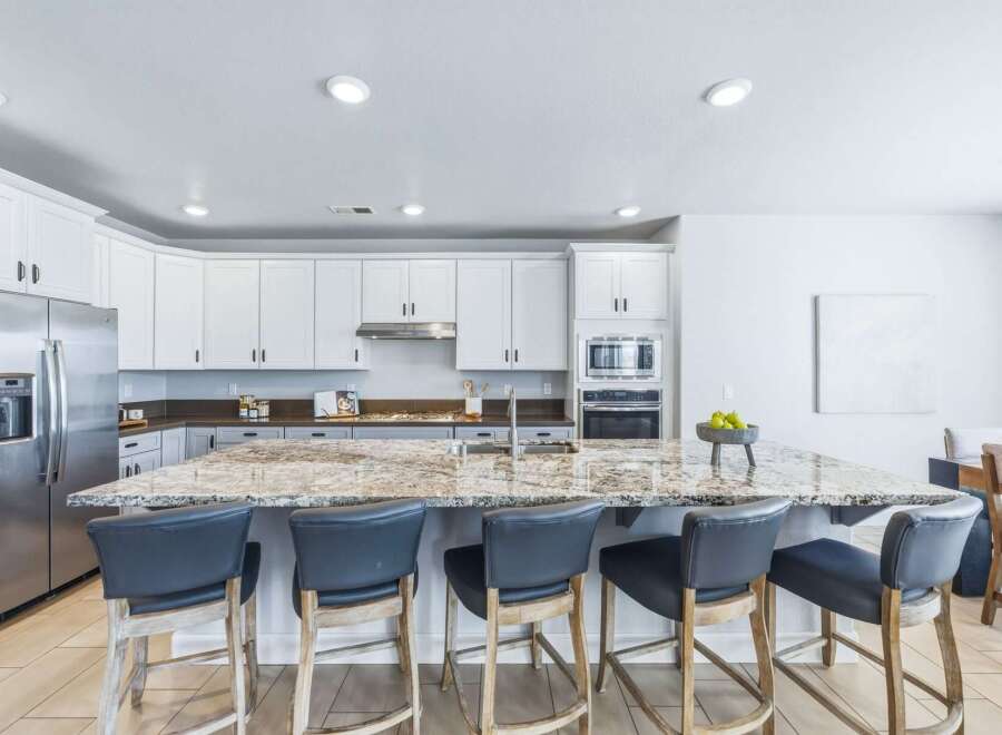 Experience luxury in this stunning kitchen, featuring sleek white cabinetry and a spacious granite island perfect for entertaining.