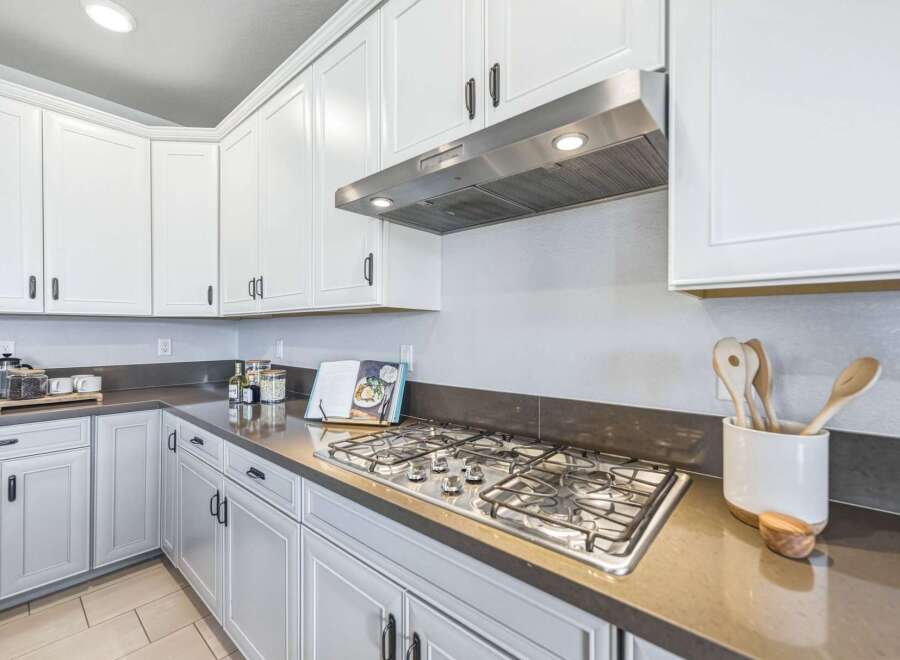 Experience culinary excellence in this modern kitchen, featuring sleek white cabinetry and a professional-grade gas range.