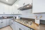 Experience culinary excellence in this modern kitchen, featuring sleek white cabinetry and a professional-grade gas range.