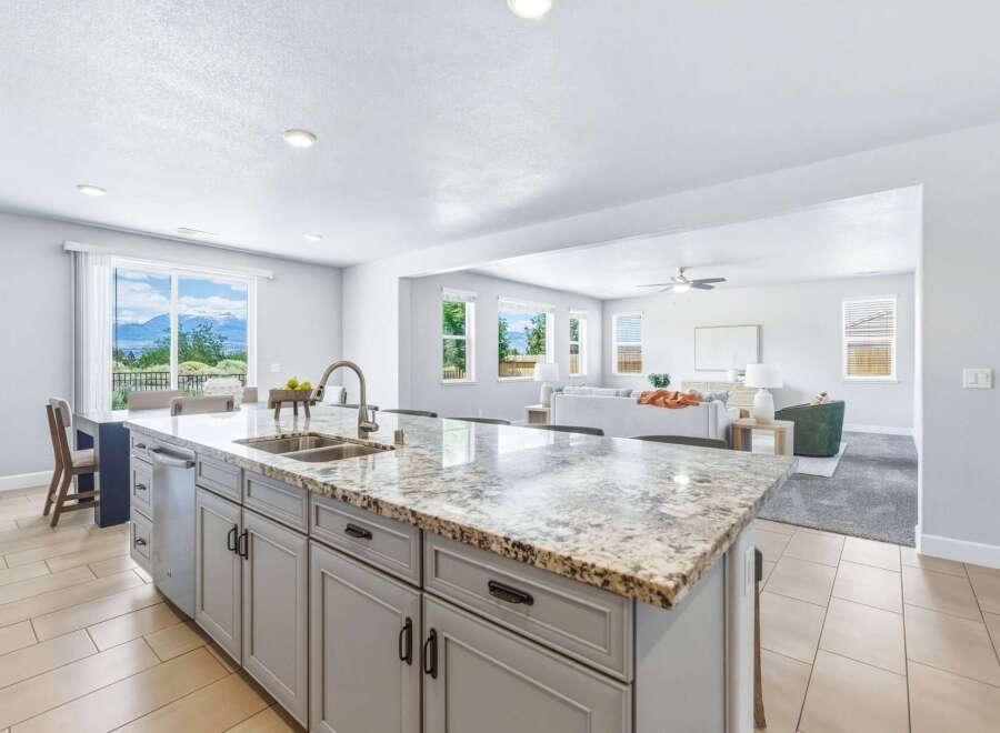 Experience breathtaking mountain views from this stunning kitchen, featuring a large granite island with a double sink and modern faucet.