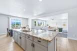 Experience breathtaking mountain views from this stunning kitchen, featuring a large granite island with a double sink and modern faucet.