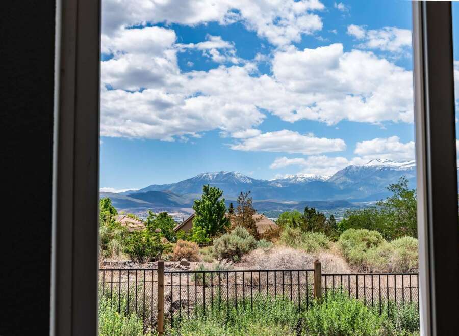 Experience breathtaking mountain views from this stunning property, framed by a clear blue sky with fluffy white clouds.