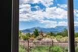 Experience breathtaking mountain views from this stunning property, framed by a clear blue sky with fluffy white clouds.