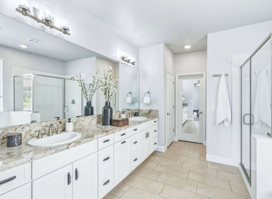 Experience luxury in this stunning master bathroom, featuring a spacious dual vanity with granite countertops and ample white cabinetry.