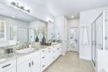 Experience luxury in this stunning master bathroom, featuring a spacious dual vanity with granite countertops and ample white cabinetry.