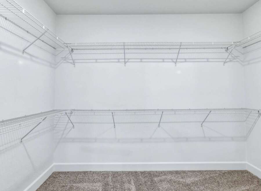 This spacious walk-in closet features ample wire shelving, perfect for organizing your wardrobe.