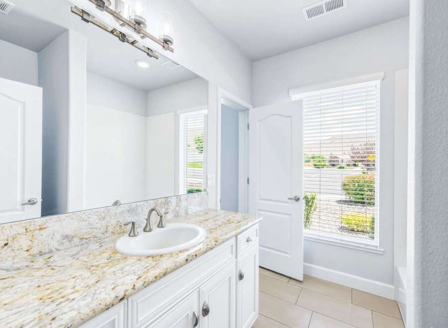 This bright and airy bathroom features a stunning granite countertop with an undermount sink and elegant brushed nickel fixtures.