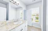 This bright and airy bathroom features a stunning granite countertop with an undermount sink and elegant brushed nickel fixtures.