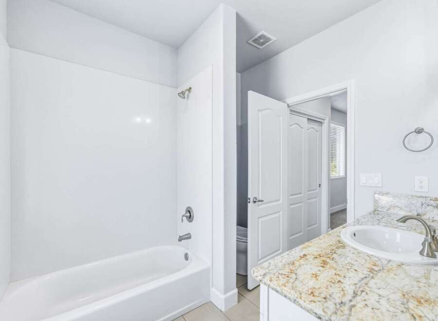 This bathroom features a pristine white bathtub and shower combo, perfect for relaxing soaks or quick rinses.