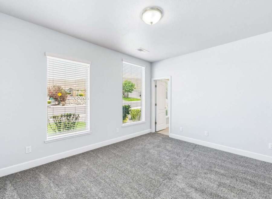 Step into this bright and airy bedroom, featuring plush grey carpeting and large windows that flood the space with natural light.