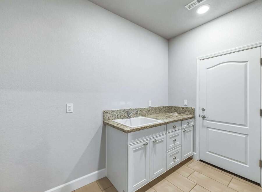 This laundry room features a spacious granite countertop with an undermount sink, perfect for all your washing needs.