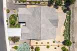 Discover this stunning aerial view of a modern home featuring a multi-faceted roof design and a spacious paved driveway.