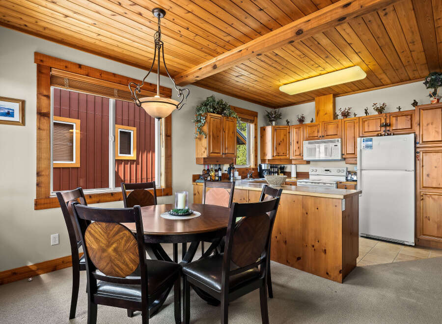 Enjoy cozy meals in this charming dining area, featuring a rich wood-toned round table with four dark leather chairs.