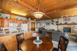 Experience cozy living in this charming mountain retreat, featuring a warm wood-paneled ceiling and a rustic stone fireplace.