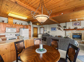 Experience cozy living in this charming mountain retreat, featuring a warm wood-paneled ceiling and a rustic stone fireplace.