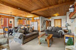 Experience cozy mountain living in this charming living and dining area, featuring a warm wood-paneled ceiling and exposed beams.